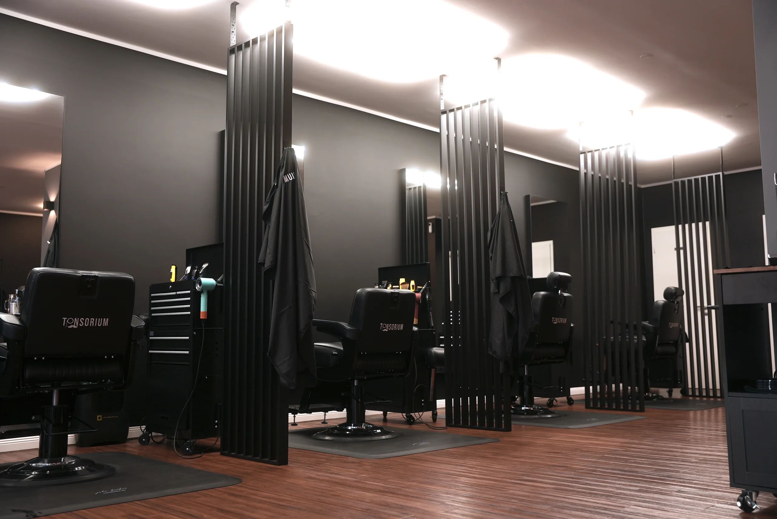 Arbeitsplätze mit schwarzen Friseurstühlen und Lamellenwänden