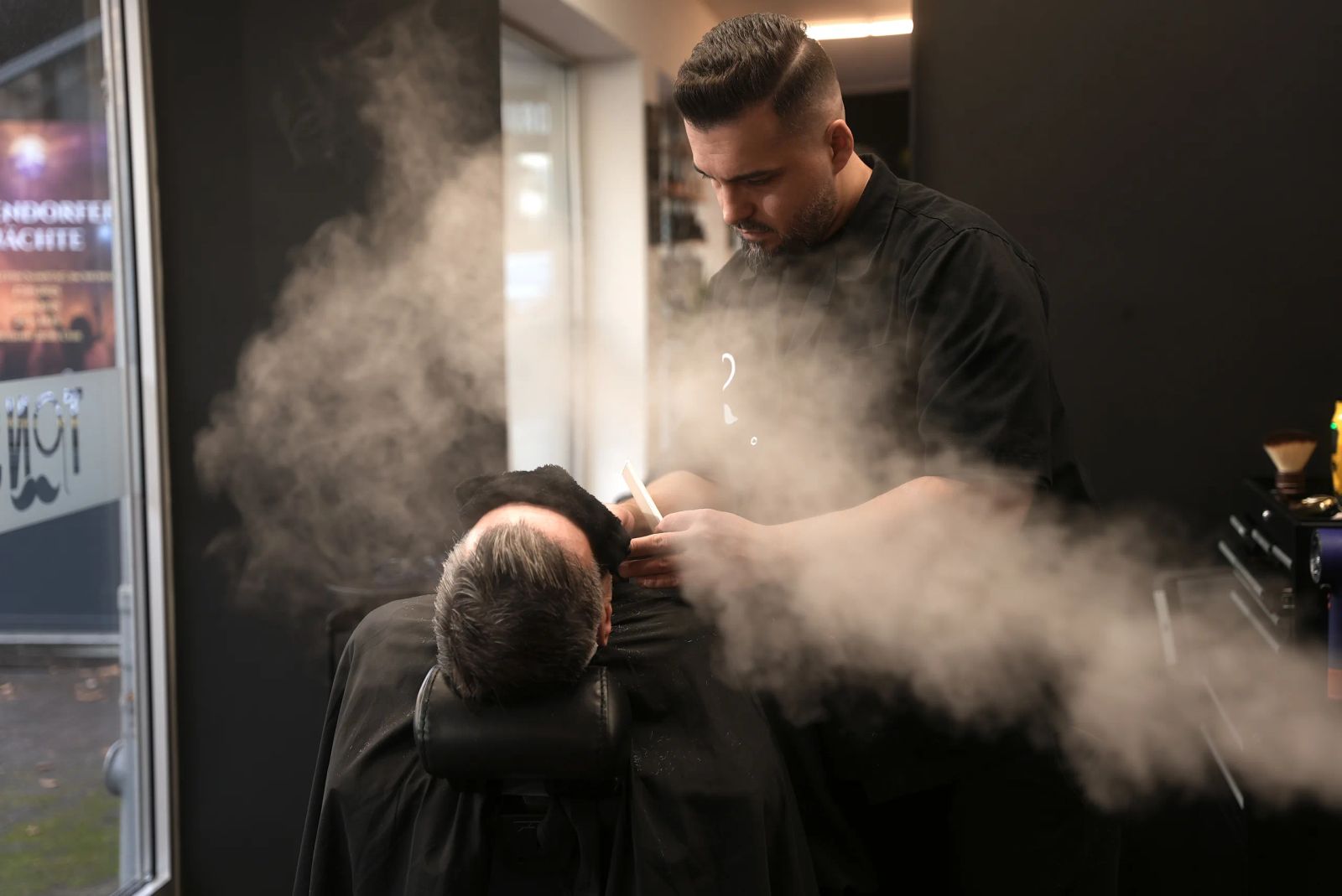 Friseur bei der Bartpflege mit warmem Dampf